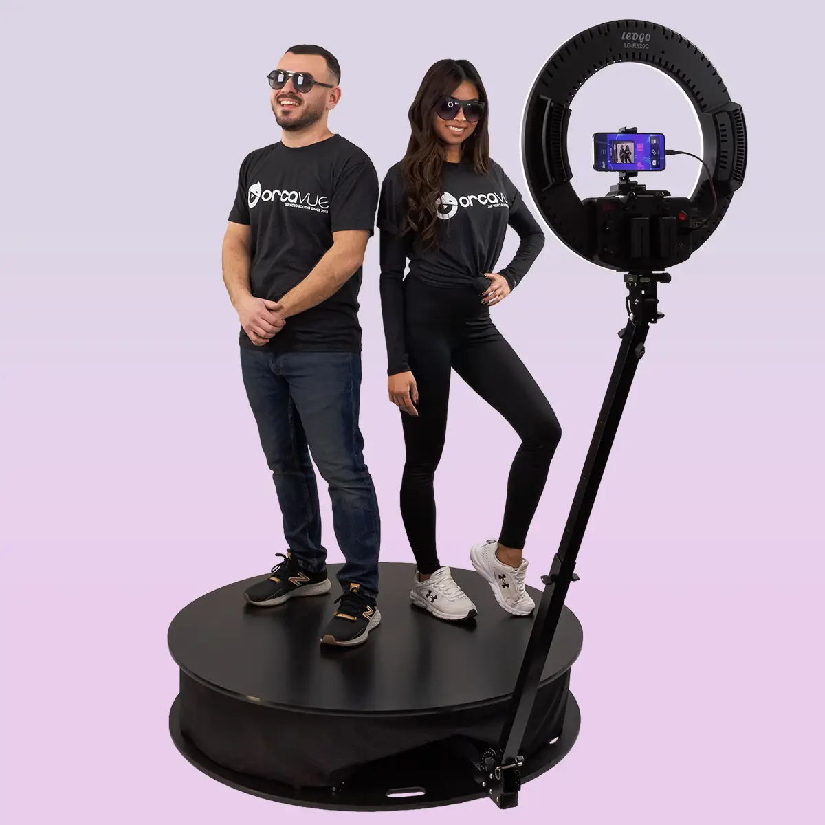 360 Photo Booth Made By OrcaVue with a male and female model striking a pose on the spinning platform