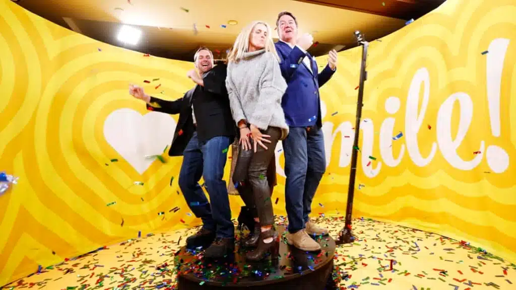 360 photo booth with two men and a woman on it against a yellow background