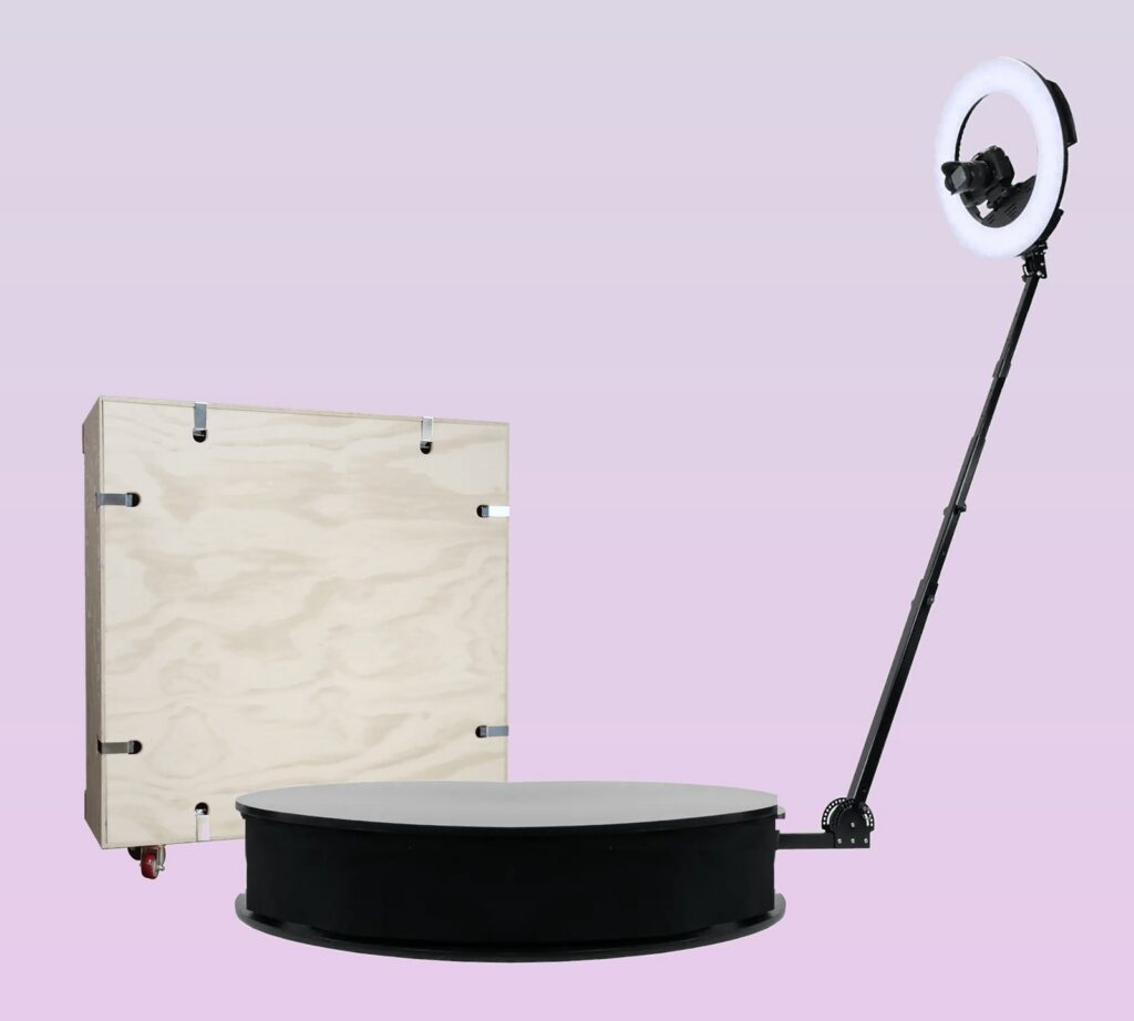OrcaVue XL 360 photo booth with ring light and DSLR camera, next to its wooden shipping crate